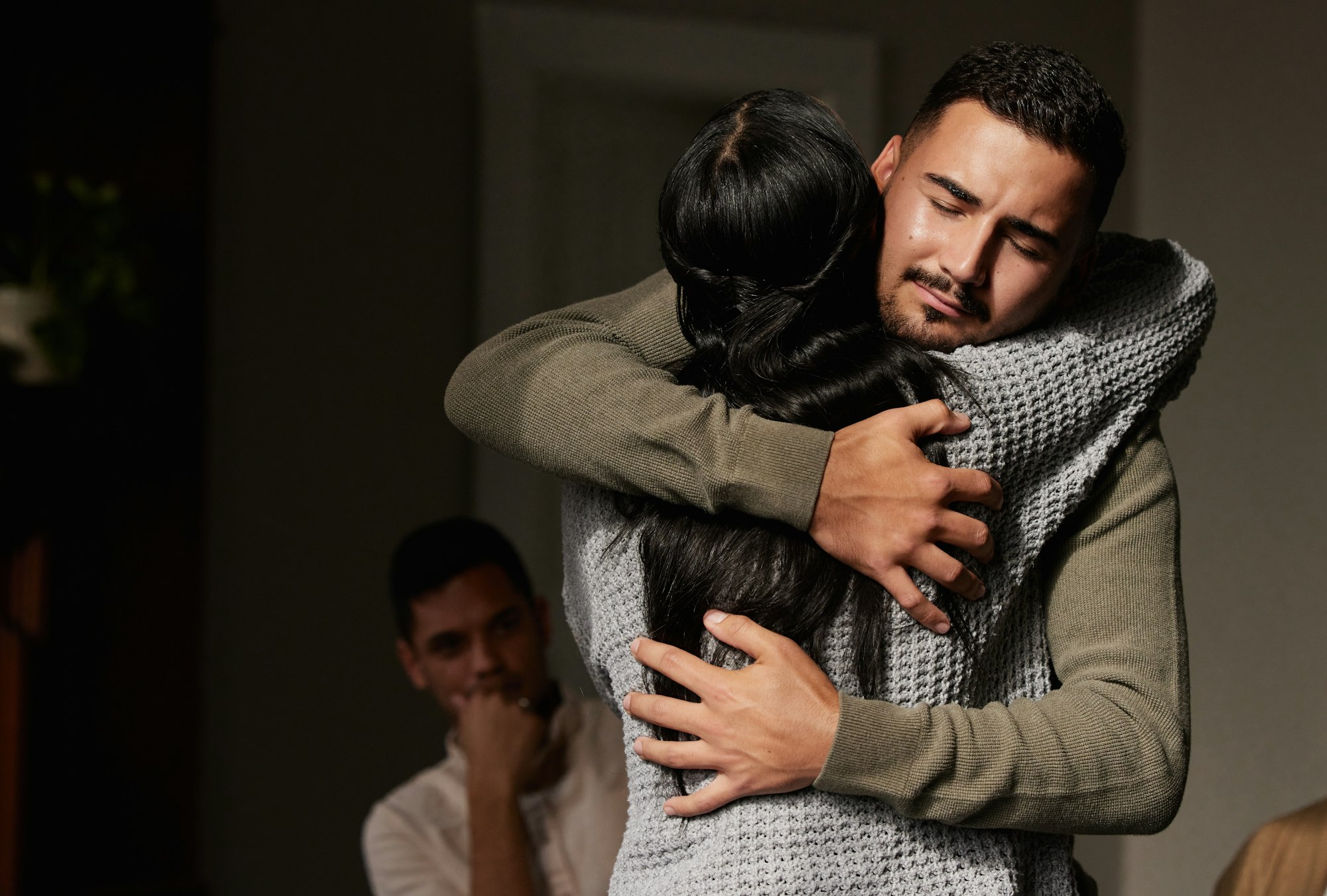 Hug, support and crying man embrace for comfort, grief and care after bad news or problems in a hom